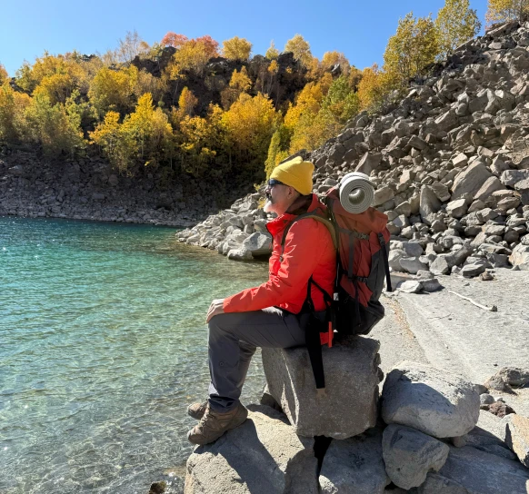 Person sitting beside rocky lakeside trail